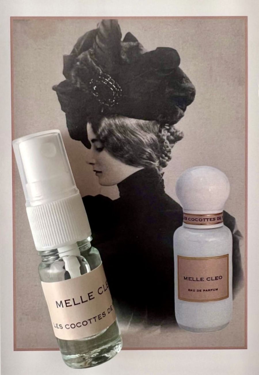 Due flaconi di profumo Melle Cleo, uno spray e uno eau de parfum, davanti a un ritratto vintage di donna con grande cappello nero, presenti nella boutique Cloud Concept Store di Brescia