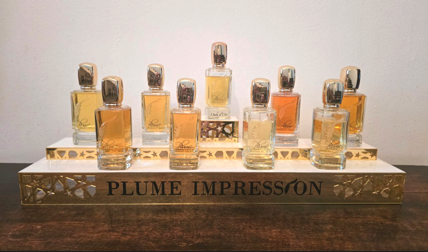 Una serie di flaconi di profumo della collezione Plume Impression disposti su un supporto decorativo.